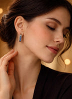 Woman wearing a pair of earrings with a warm, blurred background