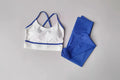 White sports bra with blue trim and matching leggings on a gray background