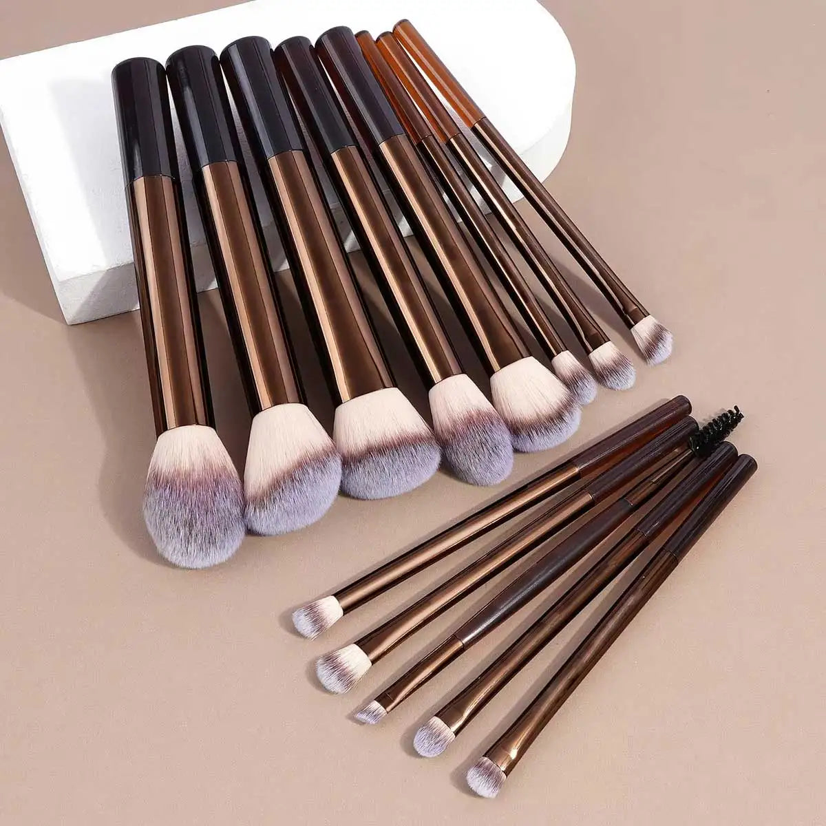 Set of makeup brushes with brown and black handles on a beige background