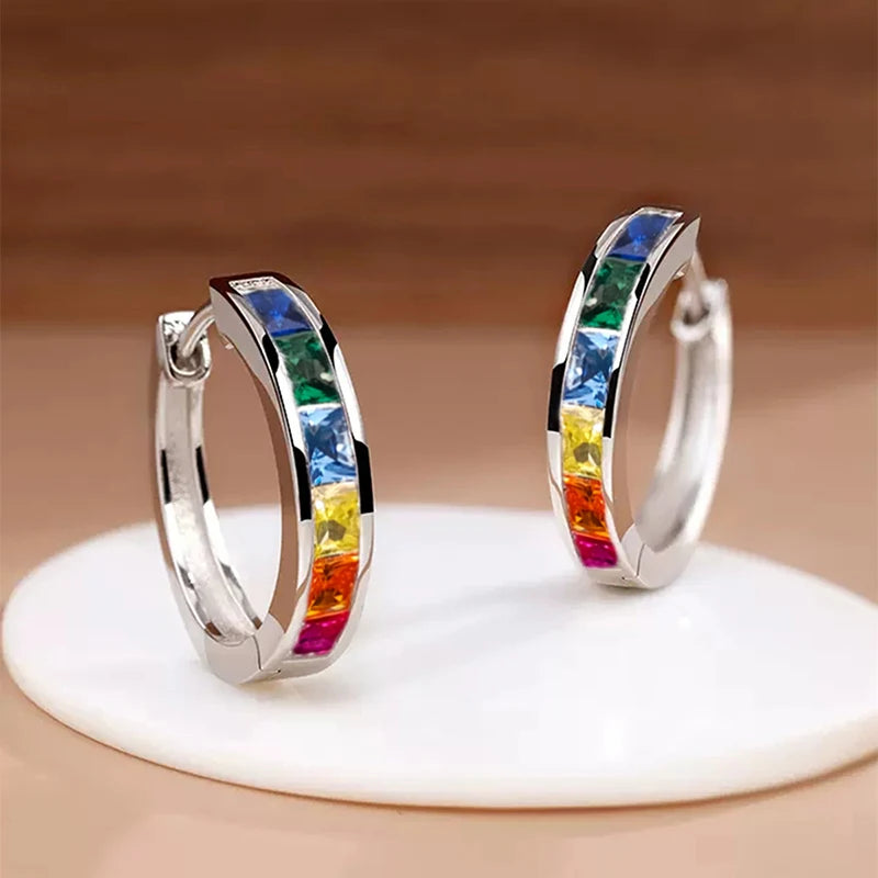 Colorful hoop earrings on a white stand with a brown background
