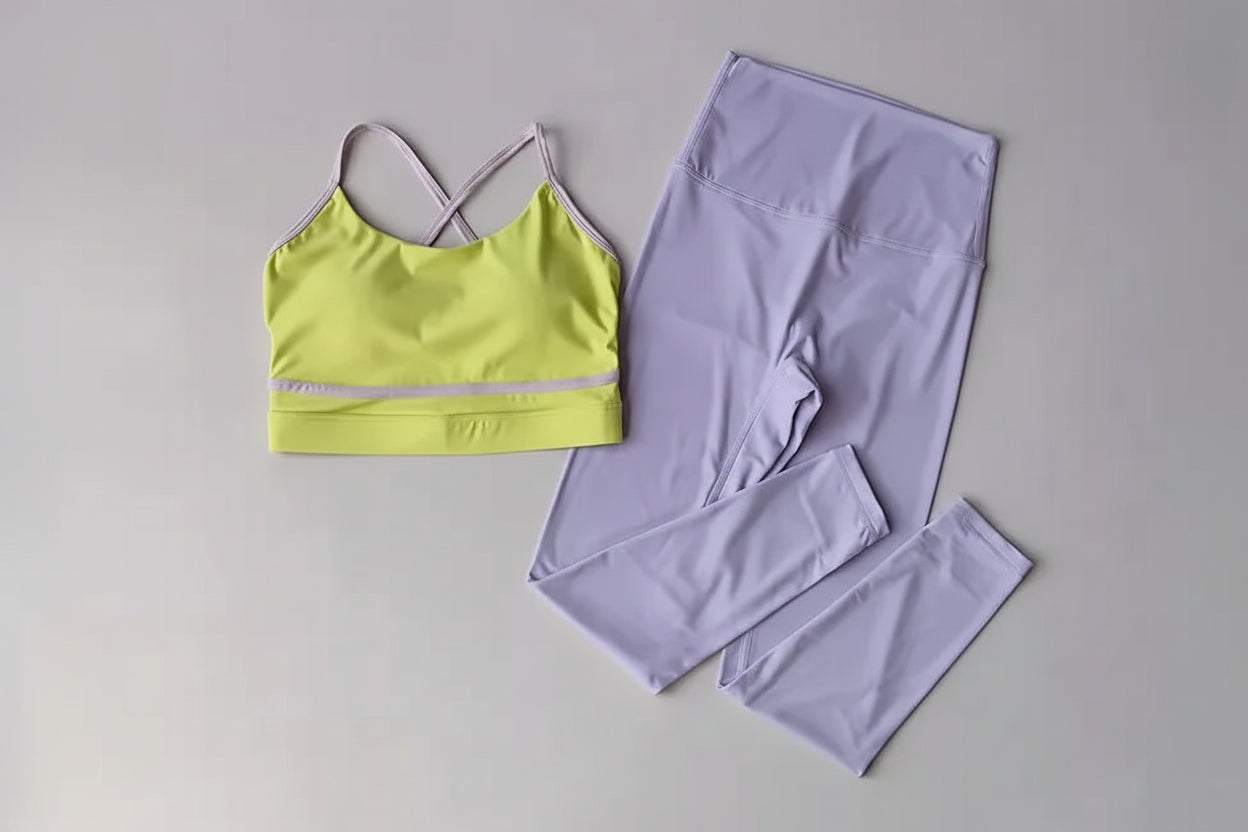 Yellow sports bra and lavender leggings on a gray background