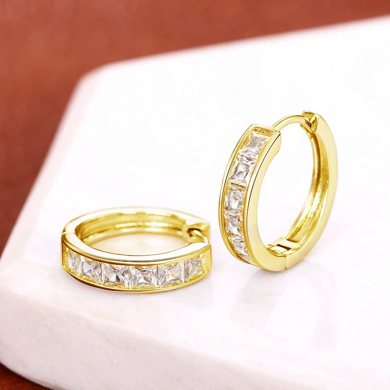Gold hoop earrings with diamond accents on a white surface.