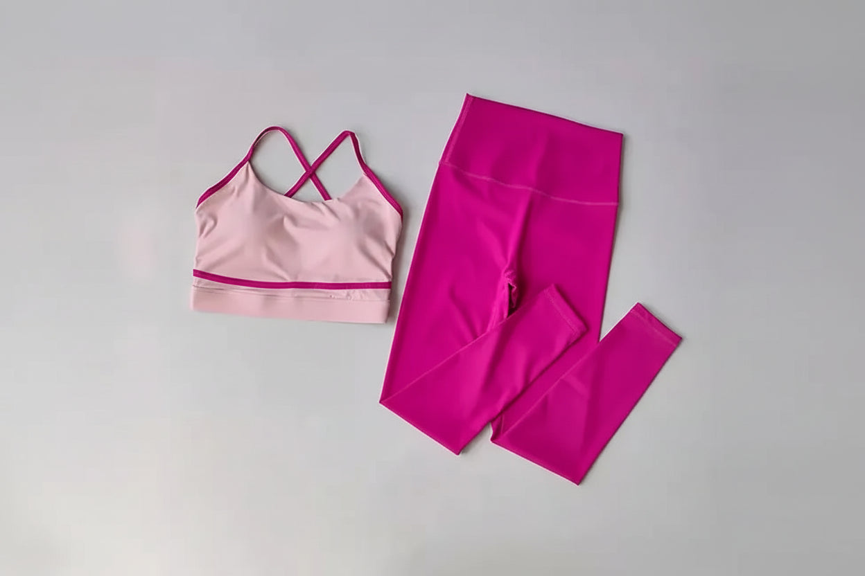 Pink sports bra and leggings set on a light gray background