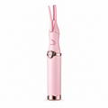 Pink heated eyelash curler with an open comb-style clamp and rose gold accents on a white background